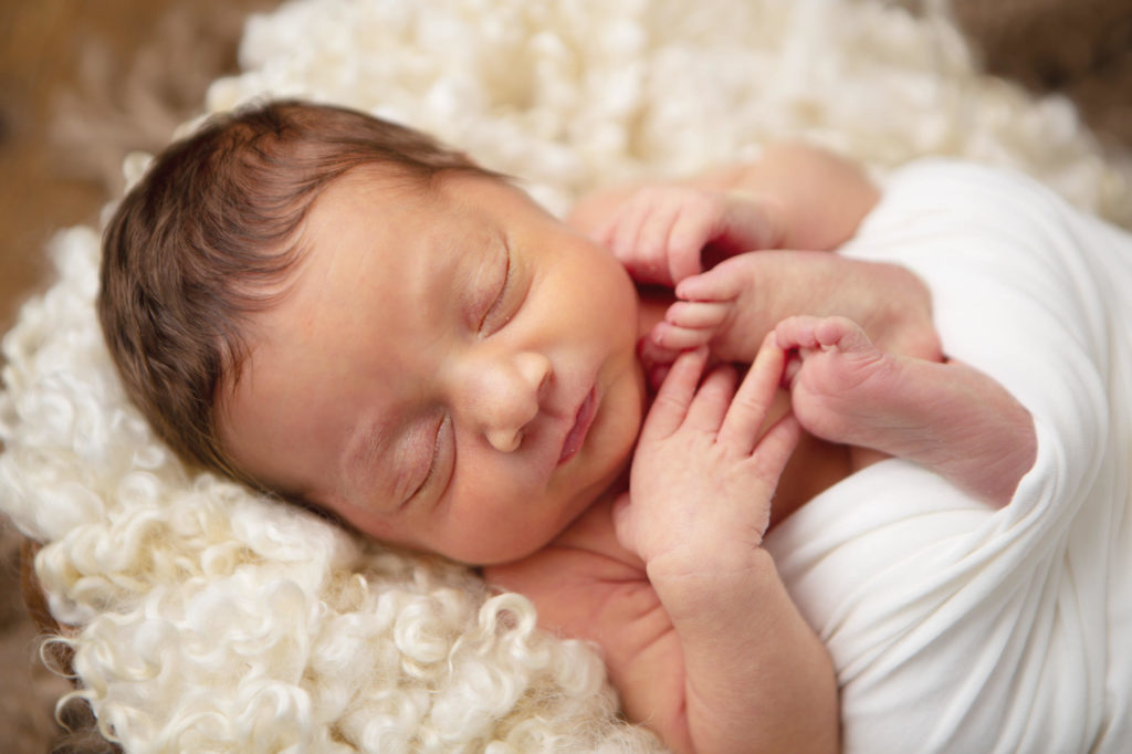 baby close up wrapped in cream and lying on curls