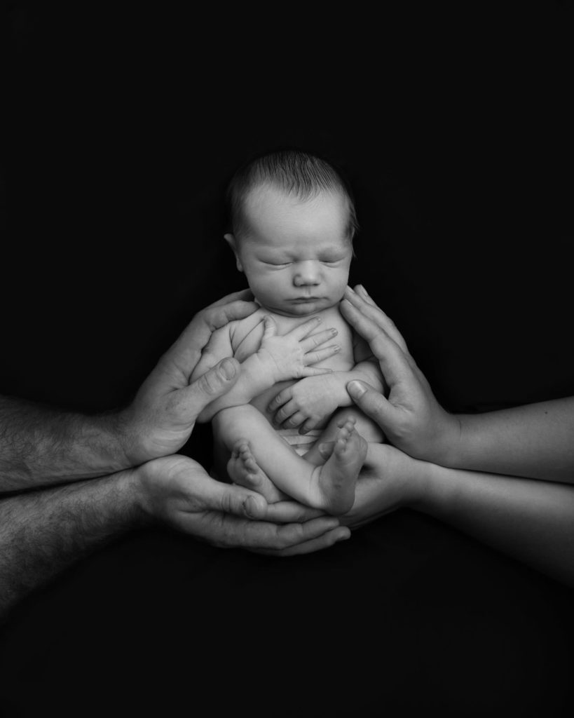 Black and white images with hands holding the baby