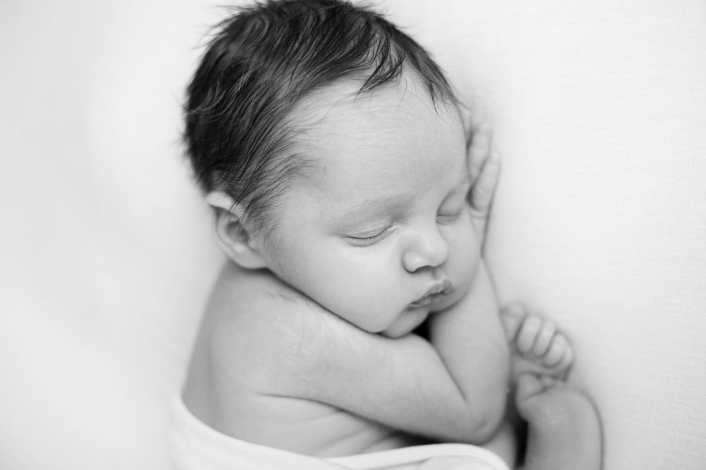 A newborn baby with lovely dark hair asleep at a newborn photoshoot