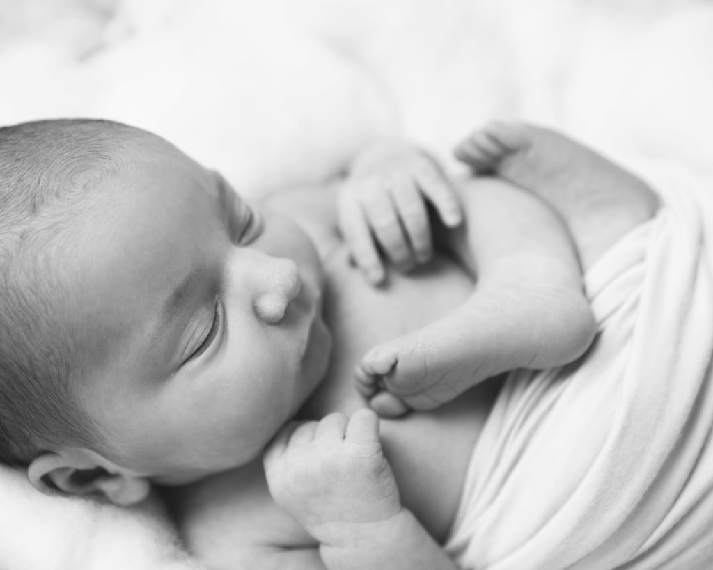 simple black and white image of a newborn baby all curled up
