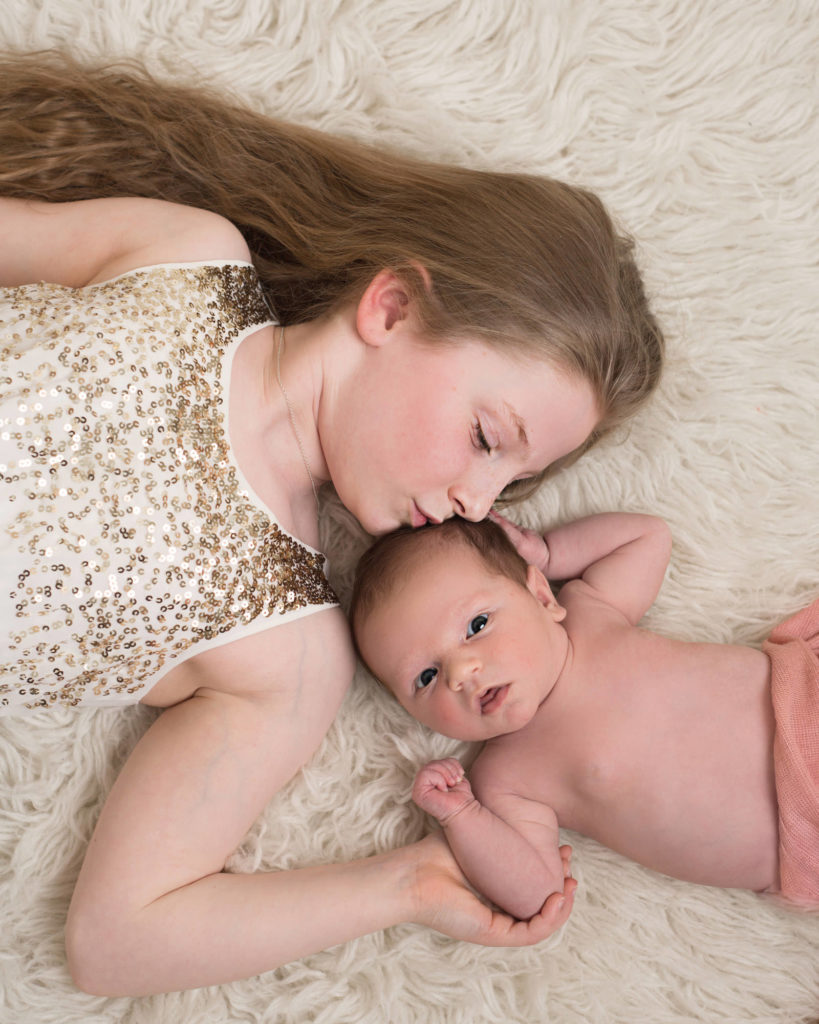 Big sister kissing her little sister in a newborn shoot based in Caerphilly