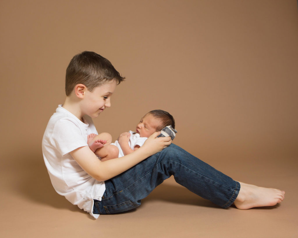 Big brother holding his new bother at their newborn photoshoot in Caerphilly