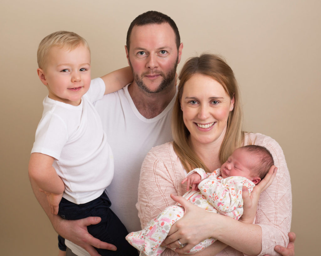 Family smiling at their newborn photoshoot in Caerphilly