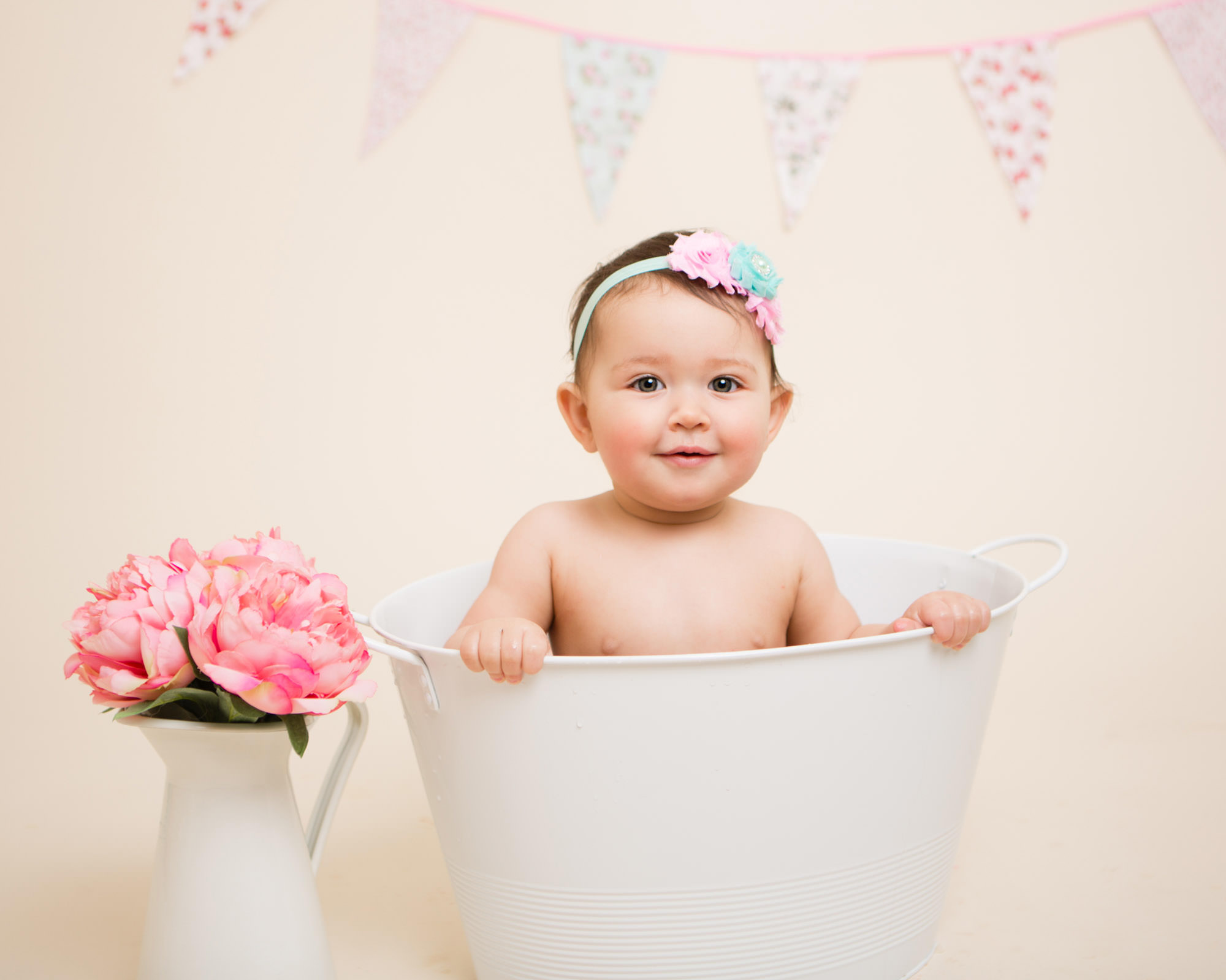 An adorable little girl holding onto the side on a white tub