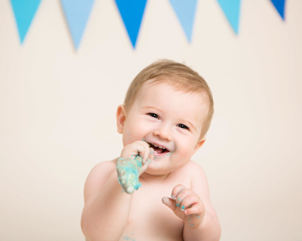a boy with a spoon in his mouth with blue icing on the end