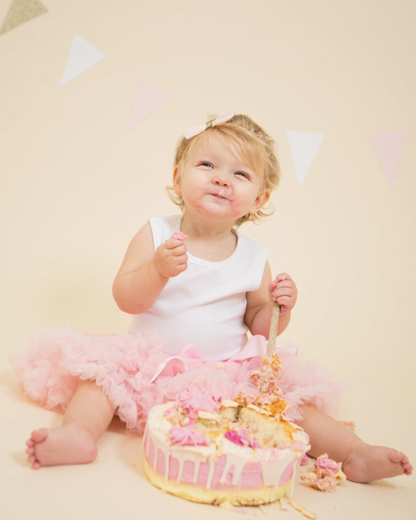 A little girl enjoying her cake with a pink frilly skirt on