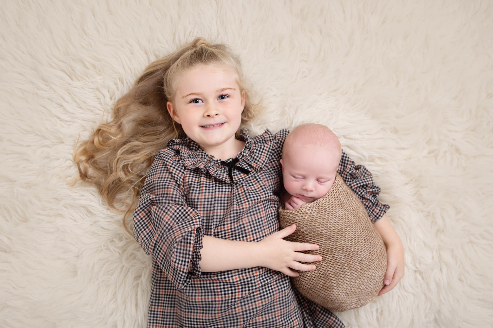 a beautiful girls with long blonde hair holding her baby brother